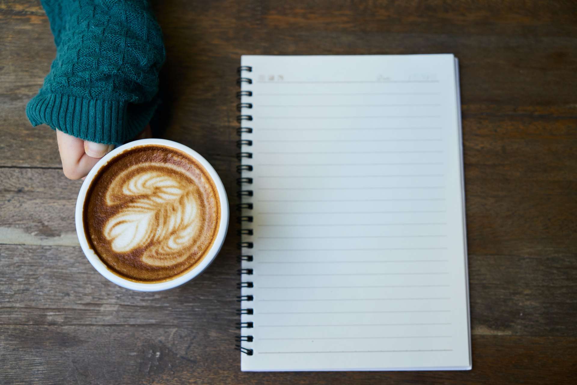 a cup of coffee next to a notebook, overhead view